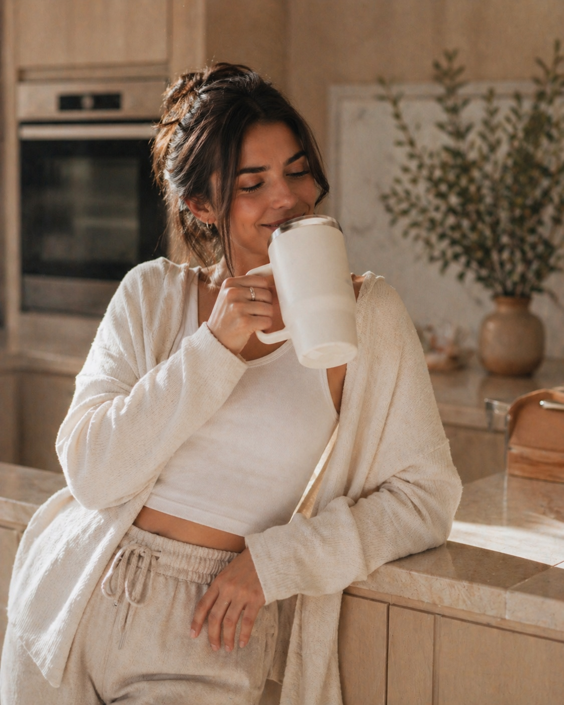 Woman drinking from a white mug in a kitchen

