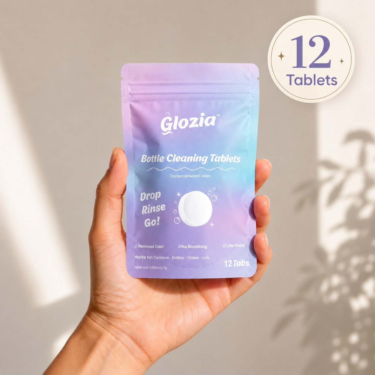 Hand holding a package of Glozia bottle cleaning tablets with a neutral background

