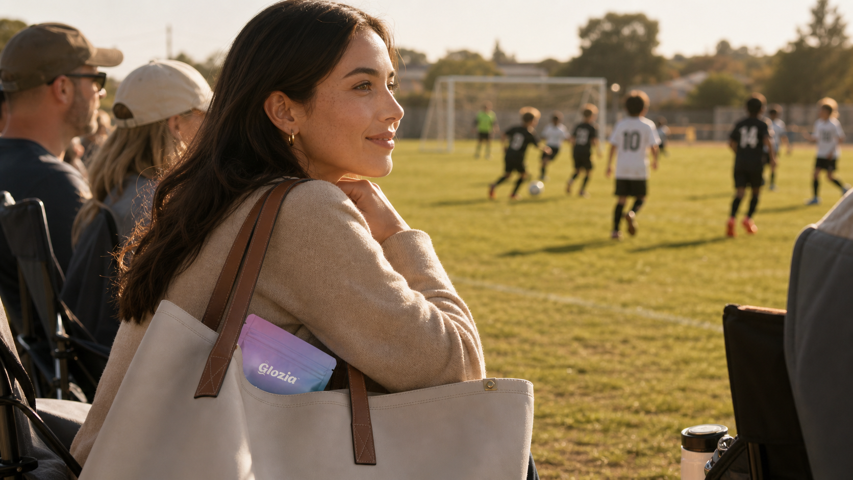 Woman with a tote bag watching a soccer game on a field

